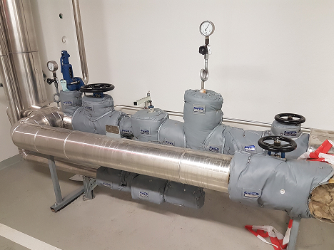 Steam PRV station with pressure reducing valve, globe valve, safety relief valve, strainer, steam trap and flanges insulated with removable, reusable blanket insulation (jacket insulation).